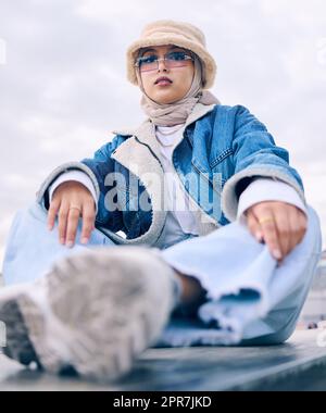 Belle jeune femme arabe posant à l'extérieur dans un foulard. Une femme musulmane attirante portant un hijab se posant à l'extérieur. Il s'agit de style et de mode. Femme de course mixte à la fois confiante et tendance Banque D'Images