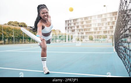 Un joueur de tennis puissant frappe une balle pendant un match. Jeune fille faisant une expression faciale pendant une partie de tennis. Un joueur de tennis en colère s'affronte dans une pratique de tennis amusante. Femme en bonne santé jouant au tennis Banque D'Images