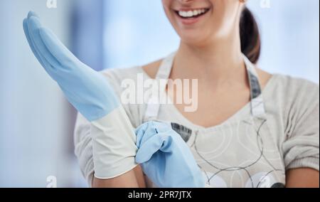 Un travailleur domestique méconnaissable portant des gants en caoutchouc au travail. Une femme de race mixte inconnue se préparant à faire des travaux ménagers Banque D'Images