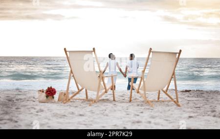 Vision d'un couple afro-américain joyeux qui passe une journée en mer ensemble. Bon petit ami et petite amie qui tient les mains tout en marchant sur la plage. Liaison de mari et de femme bienveillante sur le bord de mer Banque D'Images