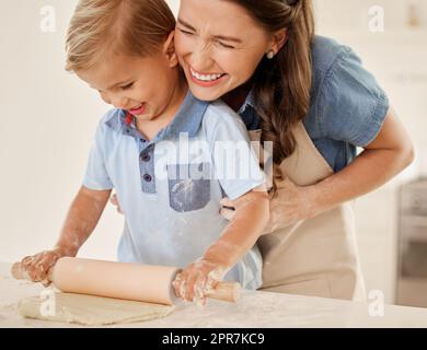 N'importe quelle activité peut être amusante. Une jeune mère roulant de la pâte avec son fils. Banque D'Images