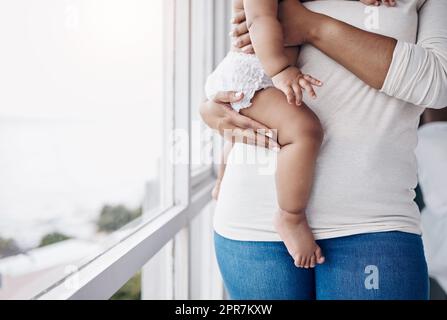 Mummys petite fille. Une femme méconnaissable se tenant à la maison et portant son bébé. Banque D'Images