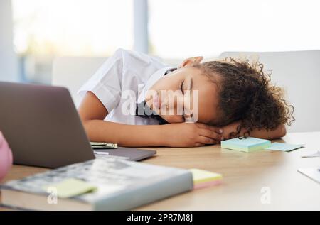 Chaque boss a besoin de leur sieste. Une adorable petite fille habillée comme une femme d'affaires dormant sur son bureau dans un bureau. Banque D'Images