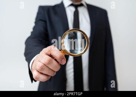 Homme d'affaires tenant la loupe d'une main. Homme ayant une loupe pour signaler des informations importantes. Homme Zooming message crutial. Cadre présentant une nouvelle idée. Banque D'Images