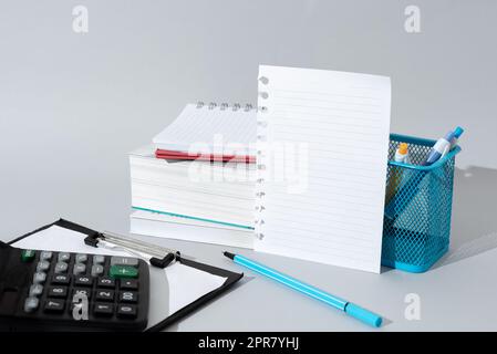 Messages importants présentés sur Note sur le bureau avec crayons, livres, presse-papiers et calculatrice. Les informations les plus importantes sont indiquées sur le mémo de la table avec les carnets et les stylos. Banque D'Images