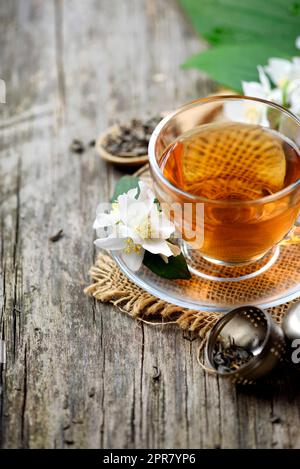 Jasmin et thé vert en tasse de thé sur la table en bois. Banque D'Images