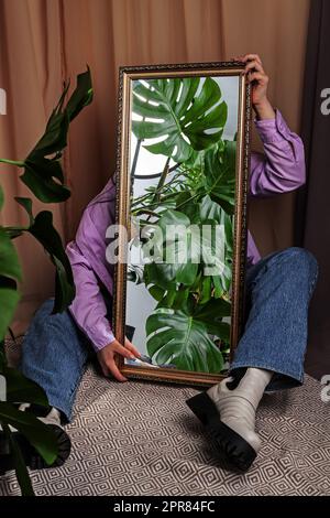 Jungles dans le miroir. Femme tient un miroir reflétant la jungle de la maison. Banque D'Images