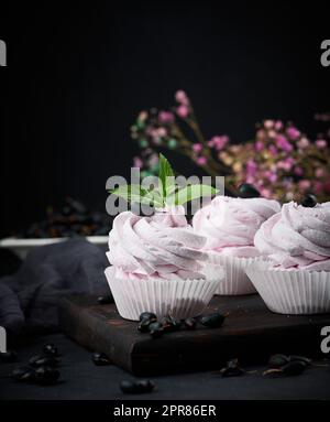 Marshmallows aux fruits martionnés dans une tasse en papier sur un plateau en bois noir, délicieux dessert Banque D'Images