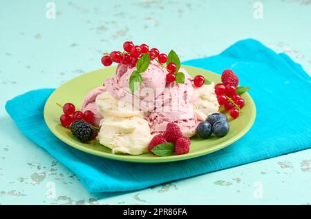 La glace à la vanille et à la framboise se ramasse sur une assiette ronde verte Banque D'Images