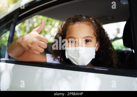 La sécurité avant tout. Portrait court d'une adorable petite fille donnant des pouces par la fenêtre arrière d'une voiture. Banque D'Images