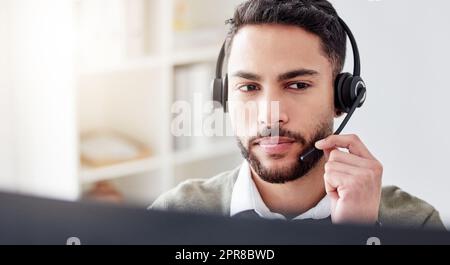 Je vous entends... un beau jeune agent de centre d'appels de sexe masculin qui travaille dans son bureau. Banque D'Images