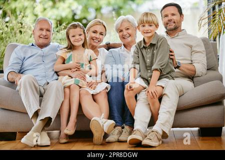 Portrait d'une famille de plusieurs générations de caucasiens souriants assis près les uns des autres sur le canapé à la maison. Heureux adorables enfants se liant avec leur mère, père, grand-père et grand-mère pendant un week-end Banque D'Images