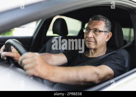 Senior dans sa 70s conduite d'une voiture Banque D'Images