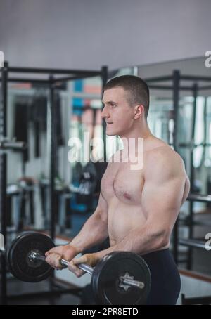 l'athlète lève la barbell d'entraînement biceps avec tout le pouvoir Banque D'Images