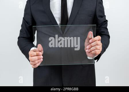 Masculin Corporate tenant du verre transparent et affichant une annonce importante. Homme d'affaires portant un costume montrant un tableau rectangulaire et faisant la promotion de la marque de l'entreprise. Banque D'Images