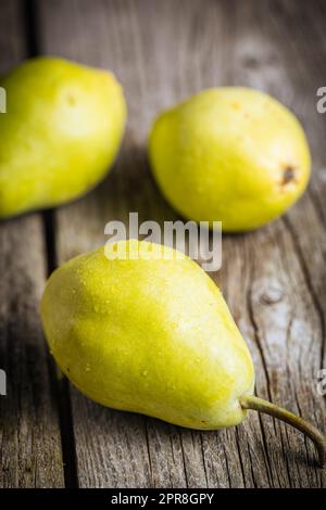 Groupe de poires vertes sur fond de bois rustique. Fruits de saison frais et savoureux Banque D'Images