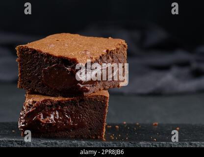 Morceaux de tarte au chocolat au brownie sur table noire, délicieux dessert Banque D'Images