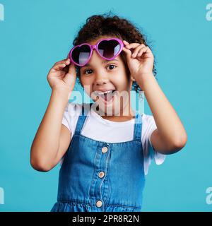 Je n'ai pas l'air cool. Une adorable petite fille posant sur un fond bleu. Banque D'Images