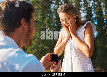 Être avec vous pour toujours serait un honneur. Un jeune homme proposant à sa petite amie dans la nature. Banque D'Images