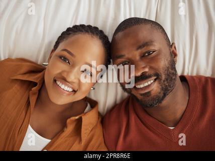 Portrait d'un afro-américain aimant allongé ensemble sur un lit, d'en haut. Joyeux jeune homme et femme souriant et regardant l'appareil photo Banque D'Images