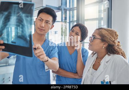 Ce qui semble être le problème ici. Un groupe de professionnels de la santé regardant une radiographie pendant une réunion dans la salle de conférence de l'hôpital. Banque D'Images