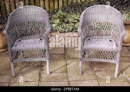 Deux chaises de jardin relaxantes et des sièges dans une cour privée et isolée à la maison pour profiter de la nature maternelle et de l'air frais. Paisible, paisible et paisible jardin avec des meubles confortables en osier Banque D'Images