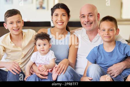 Bonne famille interraciale et se détendre ensemble à la maison. Frères et leur soeur assis avec leur père caucasien et leur mère mixte de race. Homme et femme passant du temps avec leurs enfants Banque D'Images