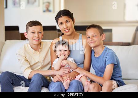 Portrait d'une famille multiraciale à la maison. Mère avec ses fils adoptifs. Jeune mère se détendant avec ses enfants. Famille mixte de course se détendre ensemble à la maison. Les garçons passent du temps avec leurs parents Banque D'Images