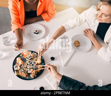 Il vaut mieux être rapide. Un groupe d'amis de sexe féminin appréciant les sushis ensemble. Banque D'Images