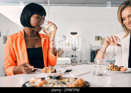 N'oubliez pas de vous hydrater. Un groupe d'amis féminins qui déguste des sushis ensemble. Banque D'Images