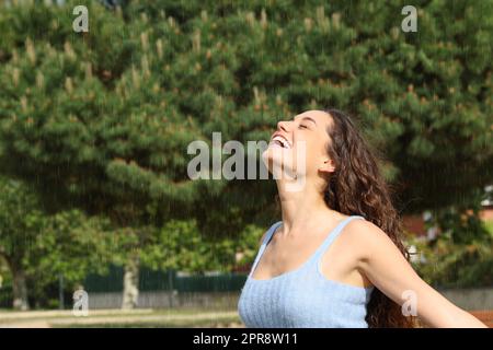 Une femme heureuse qui respire sous la pluie dans un parc Banque D'Images