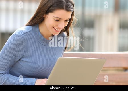 Un adolescent heureux utilisant un ordinateur portable dans un parc Banque D'Images