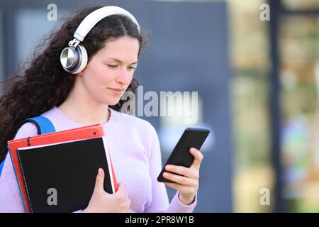 Un étudiant sérieux qui vérifie un smartphone sur un campus Banque D'Images