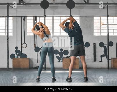 Fitness, actif et sain couple de gym étirant, se préparer et se préparer à l'entraînement, l'entraînement et l'exercice dans le centre de bien-être. Sportif, sportif ou fort homme et femme s'échauffe pour l'haltérophilie Banque D'Images