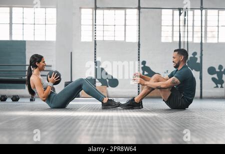 Un couple de fitness actif et sportif ou des partenaires de gym s'entraîner ensemble, faisant des exercices de base avec de l'équipement lourd. Entraîneur masculin et athlète féminin ayant une séance d'entraînement ou une classe amusante pour renforcer la force Banque D'Images