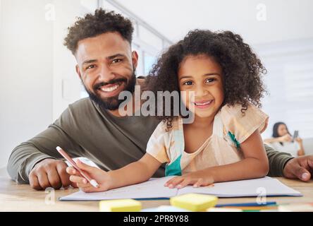 Elle adore dessiner avec son père. Un jeune père aide sa fille à faire ses devoirs à la maison. Banque D'Images