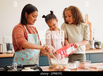 Les femmes seulement, heureux mélange race famille de trois cuisiner dans une cuisine désordonnée ensemble. Aimant parent unique noir liant avec ses filles tout en leur enseignant les compétences domestiques à la maison Banque D'Images