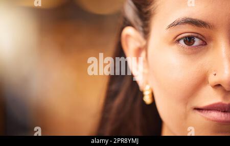 Gros plan d'un beau visage de jeunes femmes avec une peau lisse et impeccable. Femme indienne montrant sa beauté naturelle et son teint clair tout en posant avec un nez piercing, à moitié face Banque D'Images