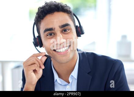 Portrait d'un agent de télémarketing de centre d'appels de course mixte souriant qui parle sur un micro-casque au bureau. Visage d'un homme d'affaires hispanique confiant et amical qui exploite le service d'assistance à la clientèle et à l'assistance à la vente Banque D'Images