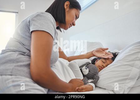 Infirmière maman. Une femme qui prend la température de ses jeunes filles à la maison. Banque D'Images