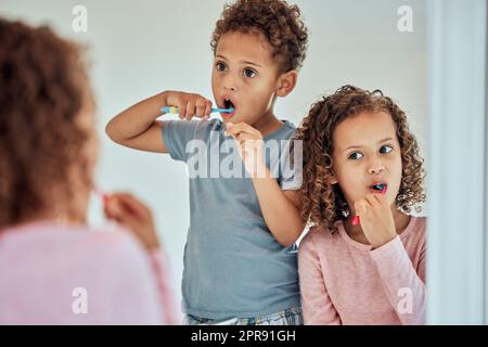 Adorable petit frère frère et sœur se brossant les dents tout en regardant dans le miroir de la salle de bains. Petite fille et garçon pratiquant une bonne hygiène buccale. Il est important de se brosser les dents deux fois par jour Banque D'Images