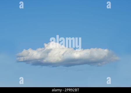 Copier l'espace avec un nuage isolé contre un ciel bleu clair lors d'une journée ensoleillée à l'extérieur. Un seul nuage blanc et moelleux flottant dans un fond d'écran paysage paisible et une scène tranquille pour l'arrière-plan de la nature Banque D'Images