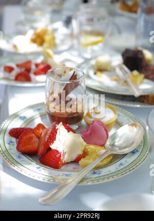 Gros plan d'un dessert sucré servi sur des assiettes et des plats en porcelaine dans un restaurant gastronomique ou un salon de thé. Détail de texture de savoureux fruits de fraise, mousse au chocolat et macarons italiens à manger Banque D'Images