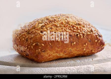 Nourriture. Gros plan de pain fraîchement cuit sur un comptoir de cuisine avec espace de copie. Pain de blé fait maison prêt à être tranché et servi comme repas. Détails macro d'un pain semé fait frais dans une boulangerie. Banque D'Images