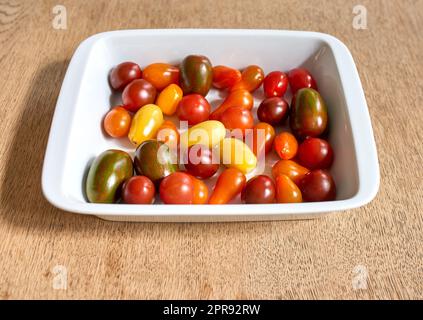 Beaucoup de tomates cerises dans un bol. Beaucoup de légumes de tomates biologiques colorés pour un plat de légumes sains. Petits fruits délicieux multicolores, parfaits pour les repas végétariens végétaliens, les hors-d'œuvre ou les en-cas Banque D'Images