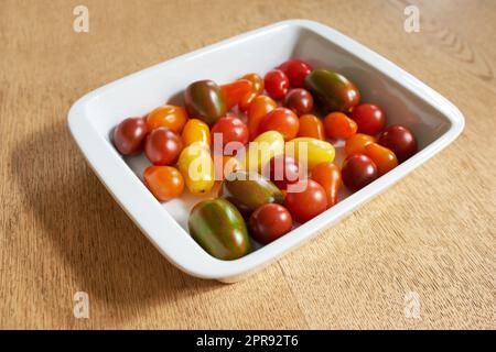 Nourriture. Gros plan de tomates roma ou cerise dans un bol en verre servi sur une table en bois pour l'alimentation, les salades saines et la nutrition. Fruits frais et biologiques cultivés dans un jardin ou une ferme agricole. Banque D'Images