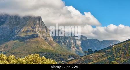 Vue panoramique sur une montagne avec des nuages qui se roulent dans un ciel bleu en été. CopySpace, vue panoramique sur un environnement naturel à la campagne. Paysage de collines et de nature Banque D'Images