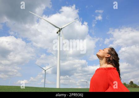 Femme en rouge respirant de l'air frais dans une ferme éolienne Banque D'Images