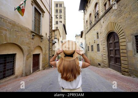 Belle fille touristique tient chapeau marchant dans la ville historique d'Arezzo, Toscane, Italie Banque D'Images