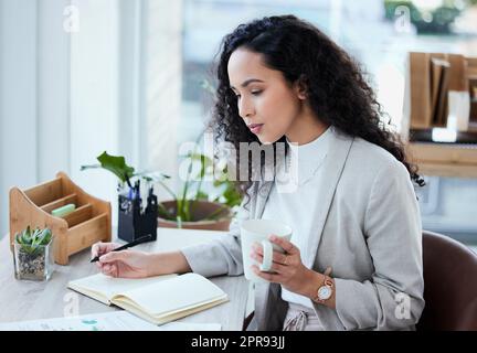 J'ai besoin de faire une lecture légère. Une jeune femme d'affaires prend des notes tout en buvant du café. Banque D'Images